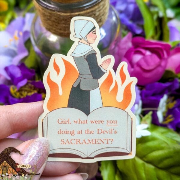 This sticker features a prayerful puritan woman, above a book opened to read, "Girl, what were you doing at the Devil's SACRAMENT?" with a background of flames.