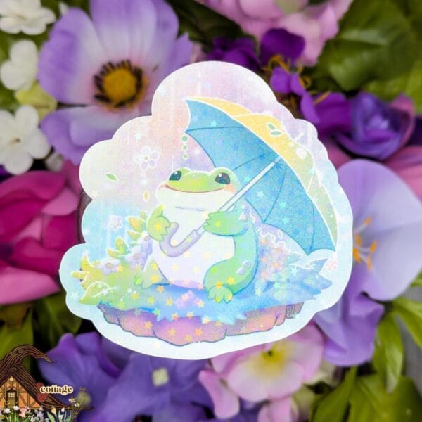 This sticker features a little green frog beneath a yellow umbrella, sitting and enjoying the rainy weather.